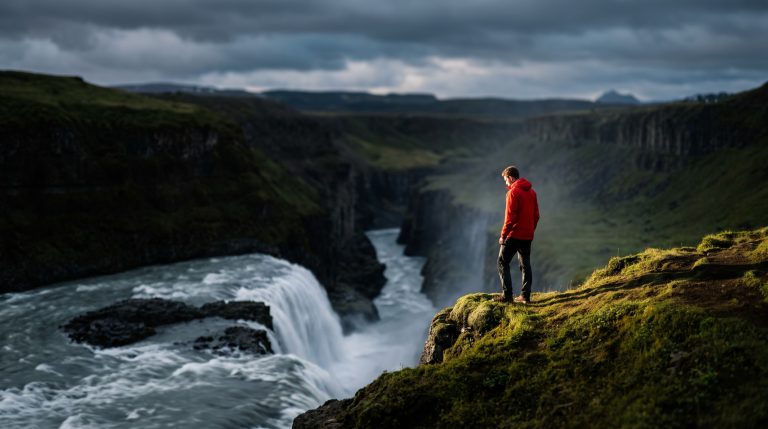 Icelandic waterfall over black volcanic cliffs with hiker for scale
