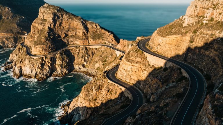 Aerial view of Chapman's Peak coastal road carved into cliffs above the ocean