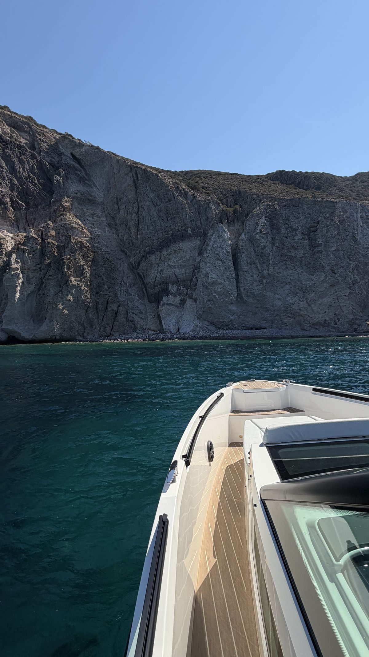 Volcanic cliffs of the Cyclades from the bow of the boat