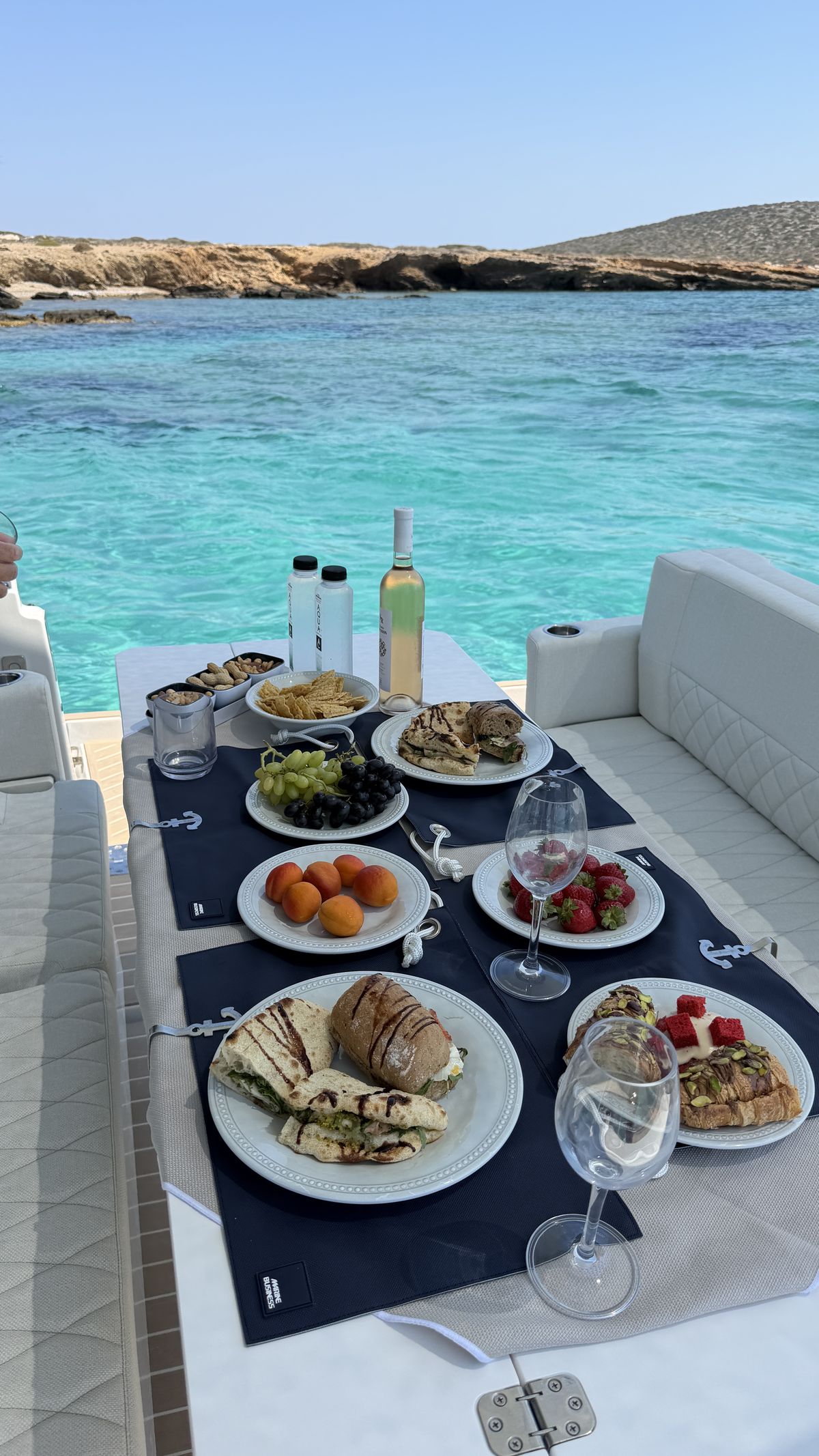 Lunch served on board over turquoise water, sandwiches, fruit and white wine